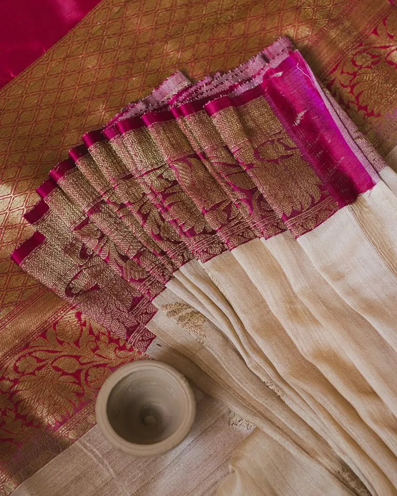 Close-up of a Silk Nagri saree with an ivory body and a magenta pallu woven with gold zari
